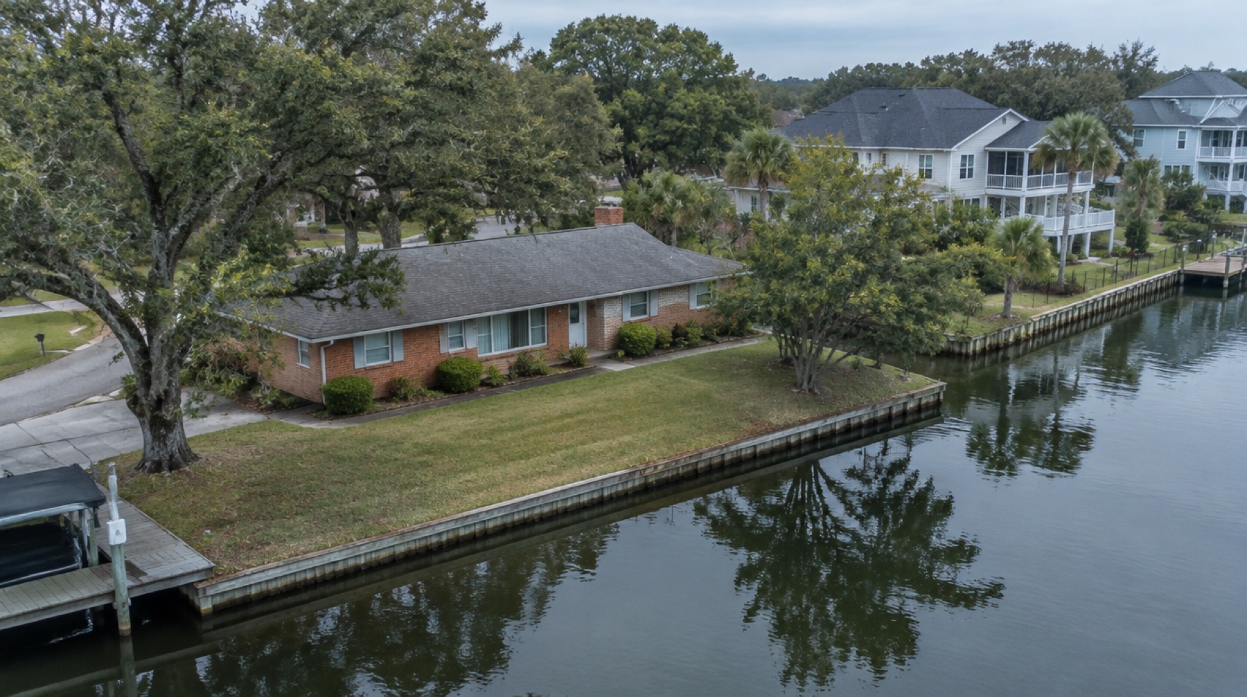 Older ranch house at ground level beside a residential canal