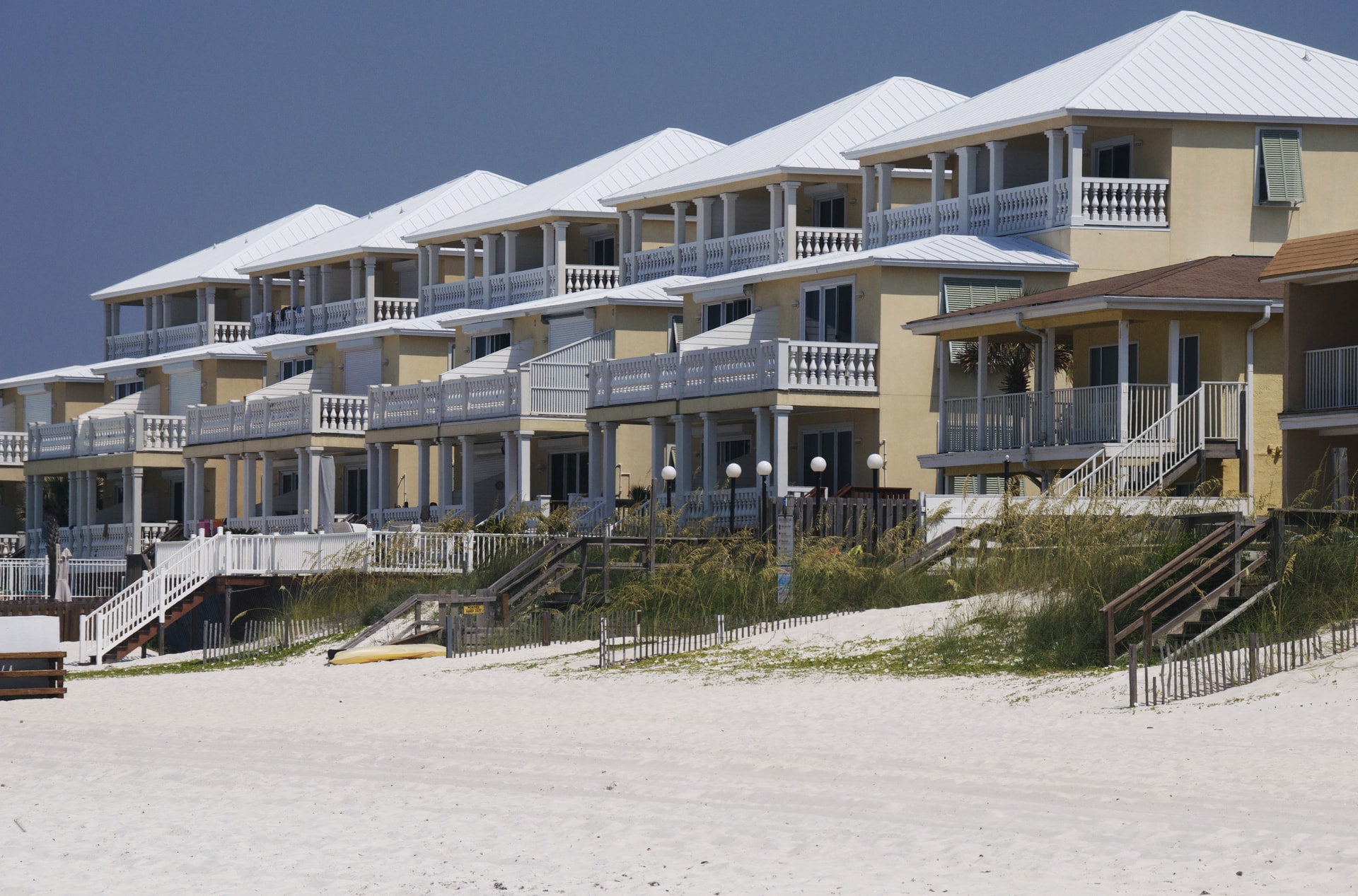 A row of two-storey beachfront condominiums behind a dune fence